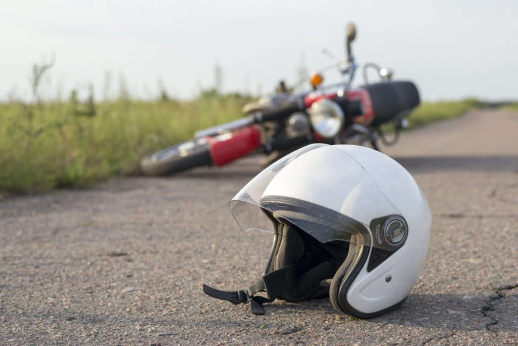 a white motorcycle helmet next to a motorcycle laying down