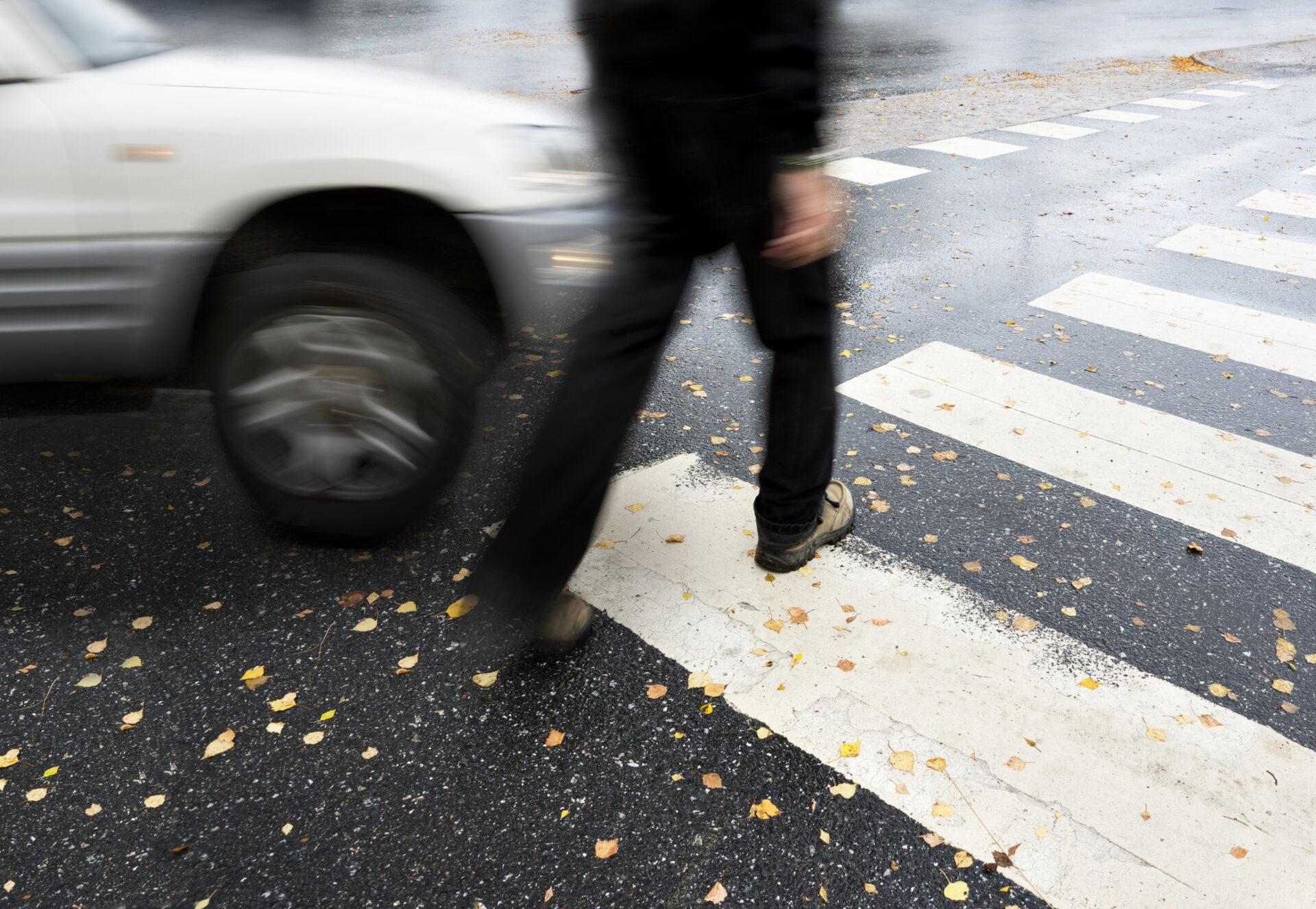 Pedestrian near moving car on crosswalk in Aurora, highlighting pedestrian accident risks.