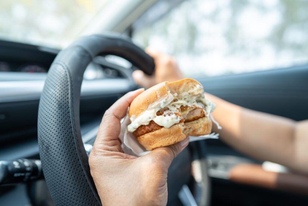 Driver holding a sandwich, potentially distracted while driving.