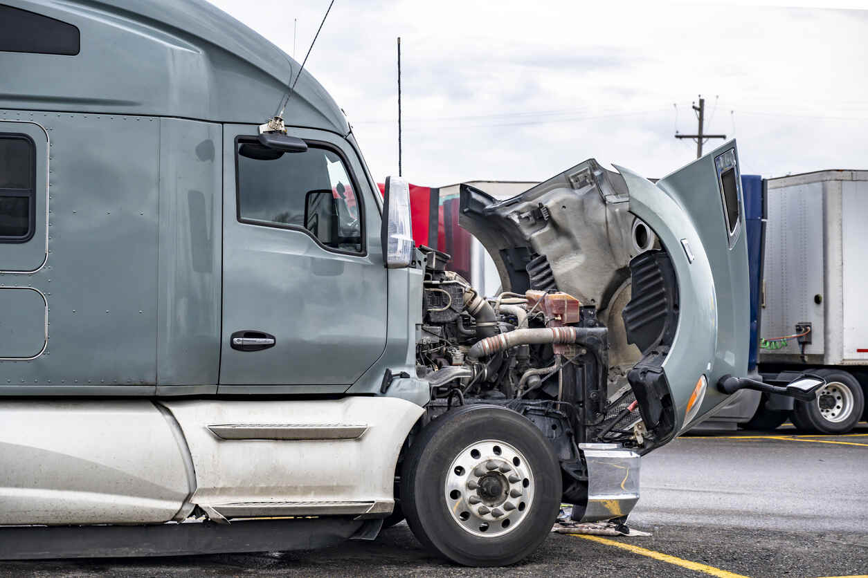 Side view of a semi-truck with its hood open for engine access.